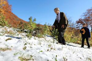 温泉街から続く山道を散策し、雪と紅葉のコントラストを楽しむ宿泊客ら＝４日朝、妙高市の燕温泉