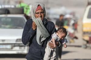 1日、イスラエルの攻撃が激化し、赤ちゃんを抱えて逃げるパレスチナ人の女性=ガザ北部ガザ市(ゲッティ=共同)