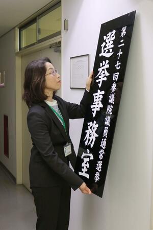 参院選の選挙事務室の看板をかける県選挙管理委員会の八幡己津子書記長=5月27日、県庁