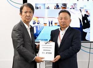 　石原環境相（左）に署名を手渡す「全国公害被害者総行動実行委員会」のメンバー＝３日午前、環境省