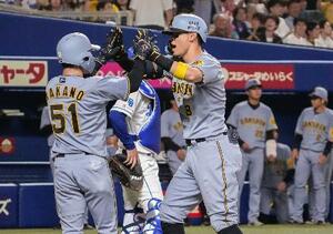 8回、3ランを放ち中野(左)とタッチを交わす阪神・佐藤輝=バンテリンドーム