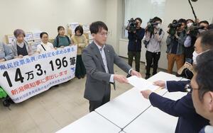 県民投票条例制定を直接請求する書類を県の担当者に提出した市民団体のメンバーら=3月27日、県庁