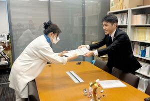 選択的夫婦別姓の導入に向け立憲民主党がまとめた法案要綱を共産党議員に手渡す黒岩宇洋衆院議員(右)=4月9日、国会