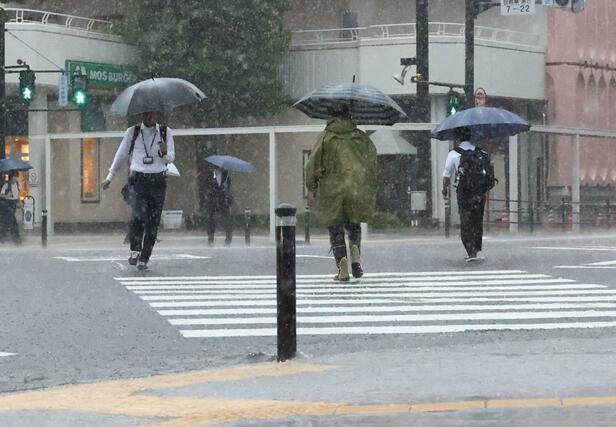 新潟市中央区では早朝から激しい雨が降り、時折雷鳴も聞こえた。新潟市中央区万代３のスクランブル交差点では、市民が傘を差したり、雨具を着たりして足早に交差点を横断していた＝７月２５日