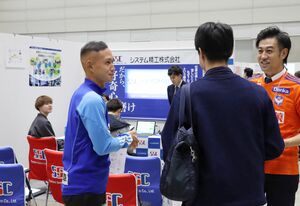 パートナー企業の求人活動の一環として、企業のパンフレットを配る早川史哉(左)=11月、新潟市中央区