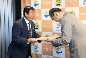 渡辺竜五市長に寄付金を手渡した刀根英夫会長(左)=佐渡市役所