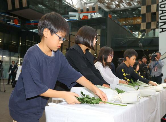 犠牲者のために献花する深沢小学校の児童たち＝１０月２３日、長岡市大手通のアオーレ長岡