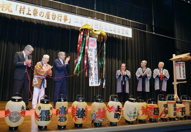 「村上祭の屋台行事」の無形文化遺産の追加登録が正式決定し、くす玉を割って喜ぶ関係者たち=11日、村上市