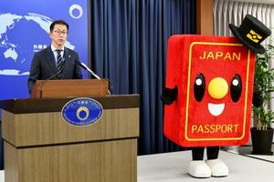 記者会見する北村俊博外務報道官とパスポートのイメージキャラクター「パスポくん」=5月、外務省