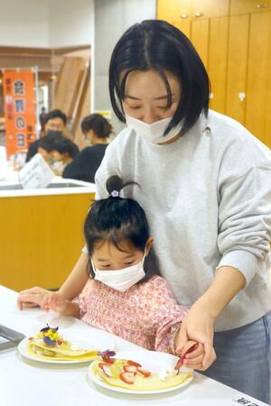 こどもの日に合わせ、こいのぼりの形をイメージしフルーツケーキ作りに挑む親子ら=4日、新潟市中央区