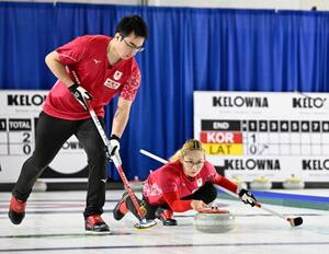 混合ダブルス1次L ドイツ戦の第2エンド、ショットを放つ小穴桃里。左は青木豪=ケロウナ(共同)