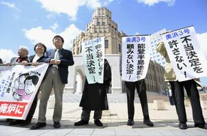 関西電力美浜原発3号機と、高浜原発1〜4号機の運転差し止めを認めない福井地裁の決定を受け、地裁前で「不当決定を許さない!」などと書かれた垂れ幕を掲げる住民ら=3月29日、福井市
