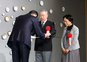 「2025年 シチズン・オブ・ザ・イヤー」に選ばれ表彰を受ける置田和永さん(中央)と起美さん(右)夫妻=29日午前、東京都千代田区