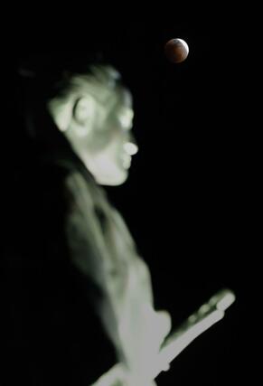 ＪＲ高知駅前の土佐三志士像の上空に見られた月食。この後、皆既となる前に雲に隠れた＝３日午後７時５３分