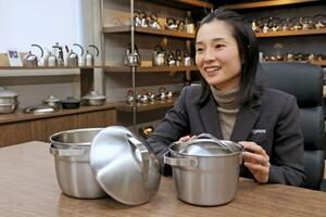 2月に発売した金属製の炊飯用鍋「ごはん鍋」を紹介する宮﨑製作所の宮﨑絢子さん=燕市