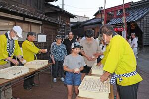 振る舞われた酒まんじゅうを受け取る地域住民ら=長岡市摂田屋3