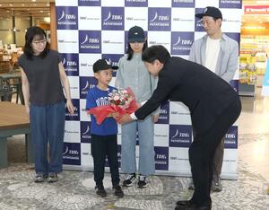 トキエアの長谷川政樹社長(手前右)から1万人目の搭乗者に記念品が贈られたセレモニー=6日、新潟市東区の新潟空港
