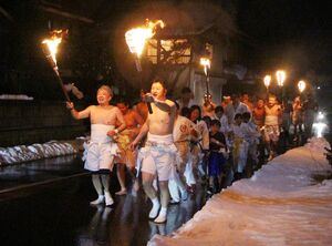 たいまつを片手に気勢を上げ夜道を駆ける「安田裸参り」の参加者=阿賀野市安田地区