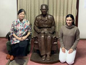 薬照寺で亡命生活を送ったバー・モウの銅像の前で記念撮影をする子孫ら=南魚沼市君沢