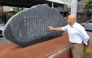 良寛の母の生家、橘屋の跡に建てられた良寛歌碑に見入るアレクサンドル・ジュアンさん=佐渡市相川大間町