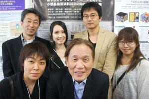 東京大の橘省吾教授(後列右から2人目)の発表ポスターの前に集まった当時の生徒らと久好圭治さん(後列左)