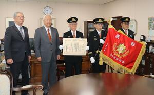 日本消防協会から授与された表彰旗を披露する刈羽村消防団の幹部＝刈羽村役場