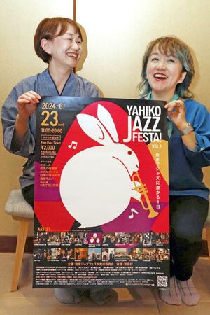 弥彦ジャズフェスタのポスターを持つ吉川ナオミさん(右)と川上志保さん=弥彦村弥彦