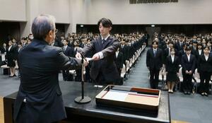 新採用の職員を代表して花角英世知事から辞令を受け取る福祉保健総務課の長谷川楓真さん＝１日、新潟市中央区