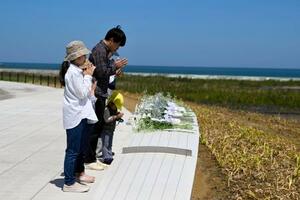 　福島県復興祈念公園で献花し、手を合わせる家族＝２日午後