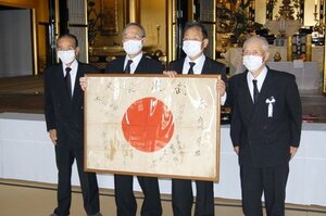 返還された日章旗を持つ古川行雄さん（右から２人目）ら＝妙高市の新井別院