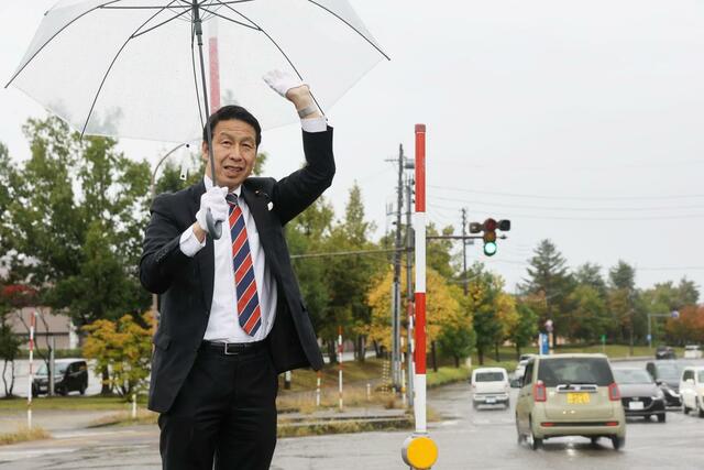 行き交う車に手を振る米山隆一さん＝１０月２８日午前７時３０分過ぎ、長岡市の蓮潟交差点