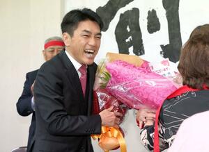 当選が決まり、支援者から花束を受け取る黒岩宇洋さん(左)=10月27日午後11時14分、新発田市中央町2