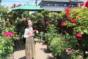 花々が咲き誇る庭でバラを手入れする西窪麗子さん=新潟市西区