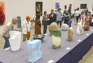 県展作品鑑賞会で、解説を聞きながら受賞作品に見入る来場者ら=25日、新潟市中央区