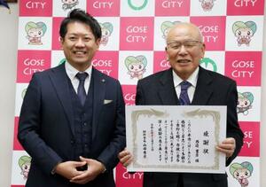 　奈良県御所市役所で山田秀士市長（左）から感謝状を受け取った西辺豊彦さん＝１２日午後