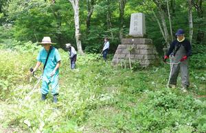 遭難碑周辺で草刈りに汗を流す信越郵政人連盟佐渡支部のメンバーら=佐渡市の妙見山