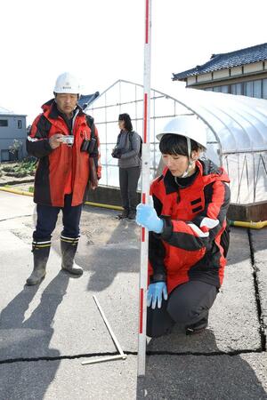能登半島地震で生じた液状化や建物被害を調べる卜部厚志教授(左)ら=1月5日、新潟市西区寺尾地域