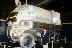 有人月面探査車「ルナクルーザー」の実物大模型。手前は監修を務めた元JAXA主任研究開発員の戸梶歩さん=11日午前、東京都江東区の日本科学未来館