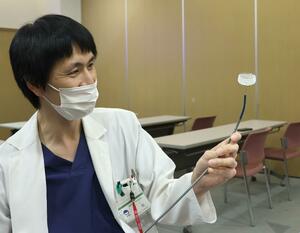 左心耳閉鎖術で使うカテーテルと左心耳にはめ込む器具を持つ医師=上越市新南町の県立中央病院