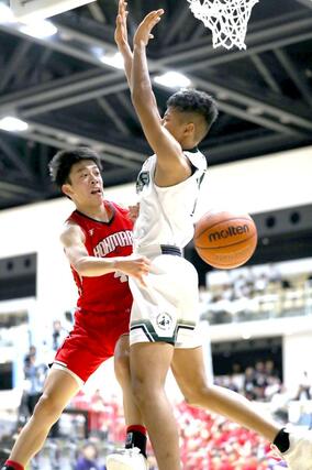 男子決勝トーナメント１回戦　実践学園－本丸　第４クオーター、ゴール下でパスを送る本丸の相馬遼大（左）＝アオーレ長岡