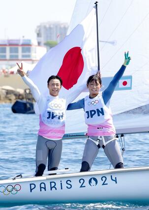 パリ五輪のセーリング混合４７０級のレースを終え、日の丸を掲げる岡田奎樹（左）、吉岡美帆組。銀メダルを獲得した＝８日、フランス・マルセイユ（共同）