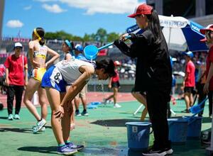 全国高校総合体育大会の陸上女子800メートル予選を終え、冷水をかけてもらう選手たち=27日、広島市のホットスタッフフィールド広島