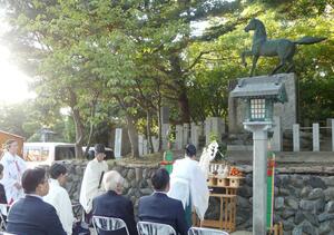 軍馬の銅像慰霊碑の前で行われた慰霊祭=23日、新潟市中央区