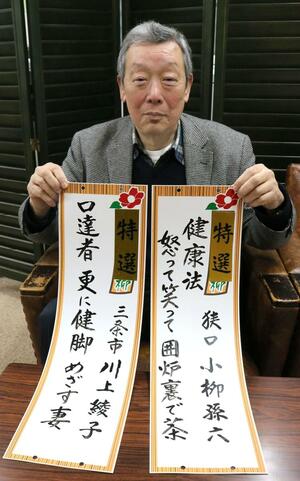 2023年秋の「ながいき川柳」入選作の短冊を手にする加茂市商店街協同組合の田辺良夫理事長=加茂市仲町1