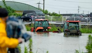 大雨で水に漬かった農業用車両=11日午後1時43分、熊本県玉名市