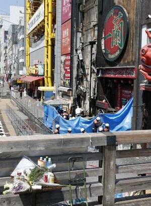 大阪・道頓堀のビル火災で行われた現場検証。現場近くには花束などが供えられていた=19日