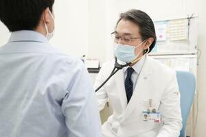 　後遺症患者を診察する岡山大病院の大塚文男教授＝岡山市（同病院提供）