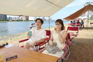 信濃川やすらぎ堤で、穏やかな風を受けながら飲食を楽しむ人たち=6月22日、新潟市中央区