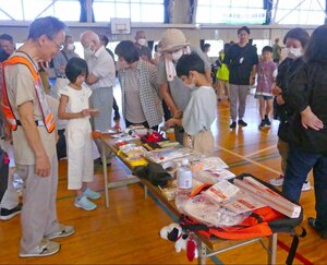 非常用持ち出し袋の見本を確認する住民たち=9月29日、新潟市西区の立仏小