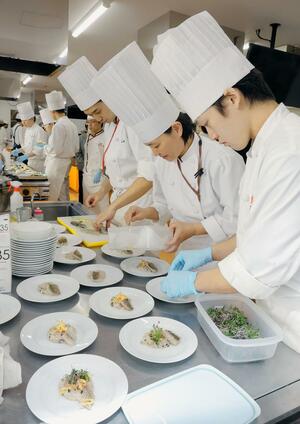 佐渡産のクロダイを使ったオリジナル料理を作る国際調理専門学校の生徒ら＝新潟市中央区
